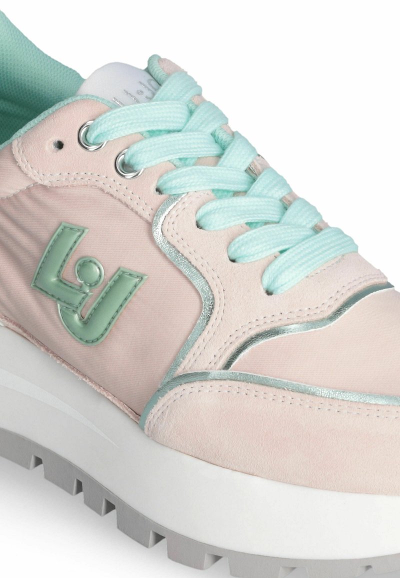 Zapatilla de color rosa claro con un upper de ante texturizado, cordones en color menta y un acento plateado brillante en el lateral. Suela blanca gruesa con fondo con relieve.
