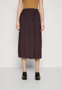 Plissé midi-hame in tumman violetin sävy, jossa on elastic vyötärö ja virtaava, teksturoitu kangas. Yhdistetty mustiin liukuviin kenkiin.