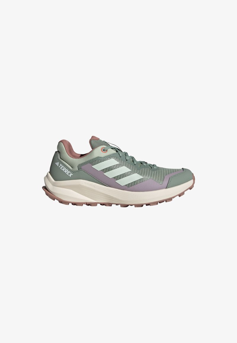Zapatilla deportiva verde claro con parte superior de malla y sintético, acentos morados, tres rayas blancas y una suela texturizada para agarre.