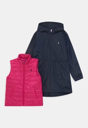 Pink polstret vest med høj krave og sidelommer ved siden af en marineblå lang jakke med hætte og lynlås, der har et logo.