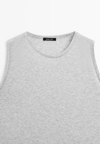 Grå ärmlös t-shirt i mjuk bomull, med rund halsringning och minimalistisk design med subtil textur och varumärkesetikett invändigt.