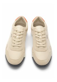 Sneaker beige con una parte superiore in rete testurizzata, dettagli in suede e lacci. Suola in gomma nera, dettagli arancioni sul tallone e logo sul lato.