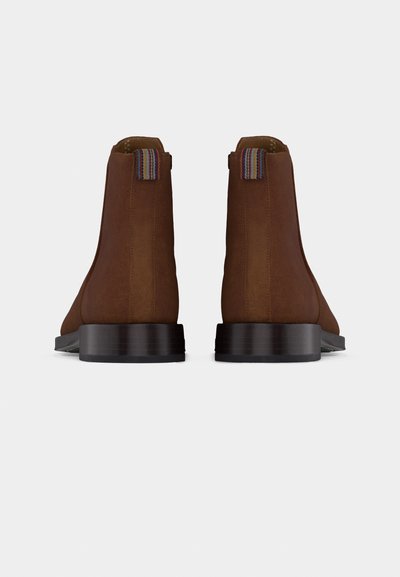 Paire de bottines en cuir marron avec talons empilés bas et languettes en tissu rayé à l'arrière, vues de dos sur fond blanc.