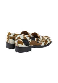 Leren loafers van koeienhuid met een gevlekte bruin-witte patroon, voorzien van een lage zwarte hak en een soepele zwarte leren voering.