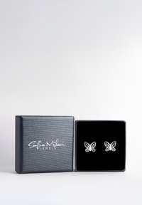 Silverfärgade örstickare i form av fjärilar, visade i en svart ask fodrad med sammet och med en texturerad grå utsida samt präglad logga.