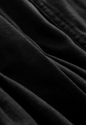 Black fabric with a textured, woven pattern, exhibiting gentle folds and a smooth finish. The material appears lightweight and soft.