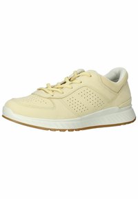 Light yellow athletic shoe with a smooth leather upper, perforated detailing, flat white midsole, and gum rubber outsole. Textile lining.