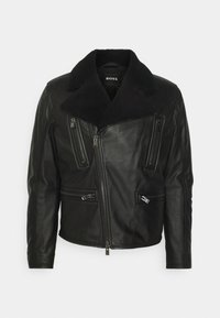 Svart läderjacka med pälskrage, som har flera dragkedjefickor och en figursydd design. Mjuk textur, slät finish och moderna hårdvaruaccents.