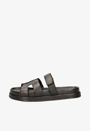 Zwarte leren sandaal met een breed strapdesign en verstelbare klittenbandsluiting. Platte zool met een gladde textuur en afgeronde randen.