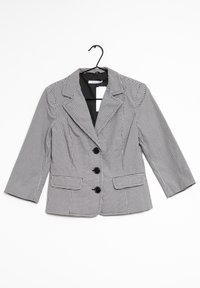 Blazer a quadri bianco e nero con collo a revers, tre bottoni neri e tasche laterali; maniche lunghe tre quarti.