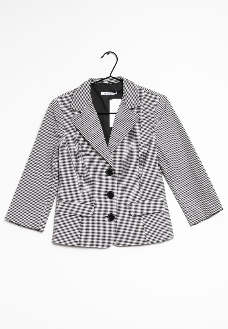Blazer a quadri bianco e nero con collo a revers, tre bottoni neri e tasche laterali; maniche lunghe tre quarti.