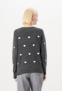 Gray sweater featuring white heart patterns, made of soft, textured fabric with a round neckline and ribbed cuffs. Casual fit with long sleeves.