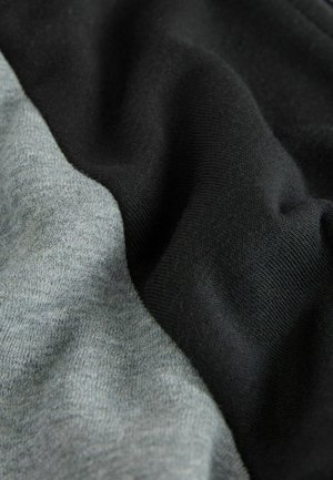 Divi divi audumi: viens gaiši pelēks, otrs melns. Abu virsmām ir strukturēti adījumi, kas demonstrē elastību un mīkstumu.