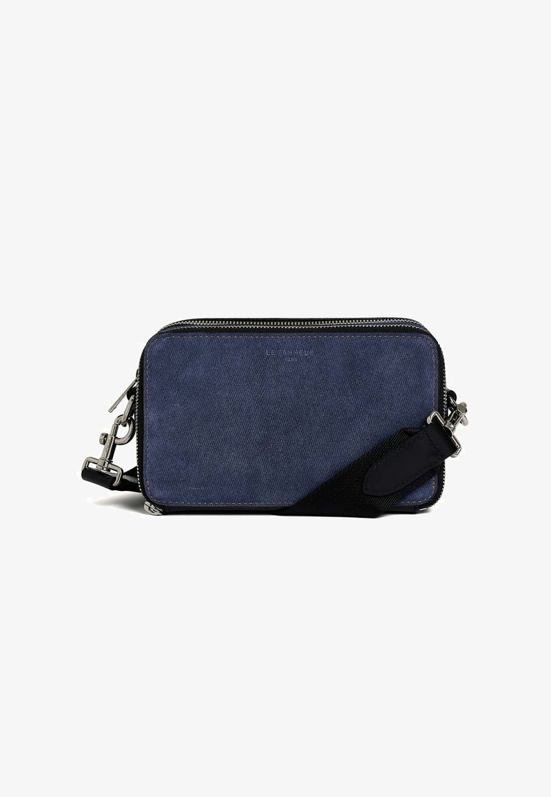 Borsa a tracolla in denim blu con dettagli neri, hardware in argento, forma rettangolare, superficie testurizzata e chiusura con zip. Presenta una tracolla removibile.
