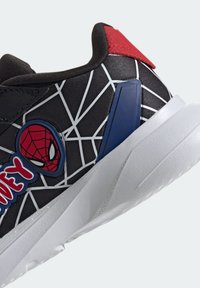 Chaussure de sport noire avec un motif de toile d'araignée blanche, présentant un accent rouge au talon et un panneau latéral bleu. Inclut un logo Spider-Man.