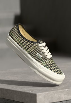 Baskets en tissu tissé avec un motif pied de poule en vert, noir et crème, dotées de lacets blancs et de semelles en caoutchouc.