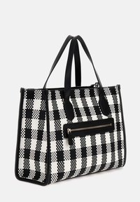 Sac fourre-tout en tissu à carreaux noir et blanc, avec deux poignées en cuir noir et une poche zippée à l'avant avec une accent noir.
