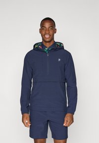 Marineblå genser med glidelås, med hette fôret i et tropisk mønster. Enkelt design, lange ermer, kombinert med matchende shorts.