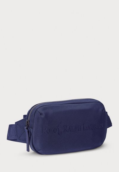 Navy blue nylon belt bag with a rectangular shape, textured surface, embossed logo, and zippered closure; features an adjustable strap.
