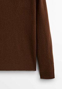 Brązowy sweter z dzianiny o gładkiej fakturze, z prążkowanymi mankietami i prostym krojem. Materiał wydaje się miękki i ciepły.
