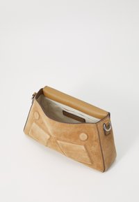 Borsa a tracolla in suede beige con una forma strutturata, dotata di un manico superiore liscio beige, cuciture decorative e accentuazioni circolari e rettangolari distintive.
