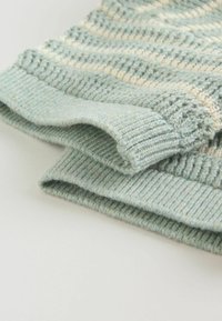 Svetlo modra pletena jopica z teksturiranimi črtami, opremljena z rebrastim robom in manšetami. Mehki material z gladkim zaključkom.