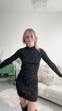 Μαύρο ριμπ φόρεμα με μακριά μανίκια, διακοσμημένο με λευκές πέρλες σε διάσπαρτο μοτίβο. Το φόρεμα έχει εφαρμοστή γραμμή και ψηλό λαιμό.