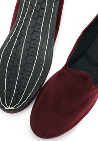 Scarpe slip-on rosse in suede con suola in gomma nera, dotate di un battistrada testurizzato e cuciture a contrasto lungo i bordi.