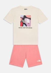 Μπεζ κοντομάνικο μπλουζάκι με πολύχρωμο αφηρημένο λογότυπο και κείμενο «THE NORTH FACE NEVER STOP EXPLORING», σε συνδυασμό με ροζ σορτς.
