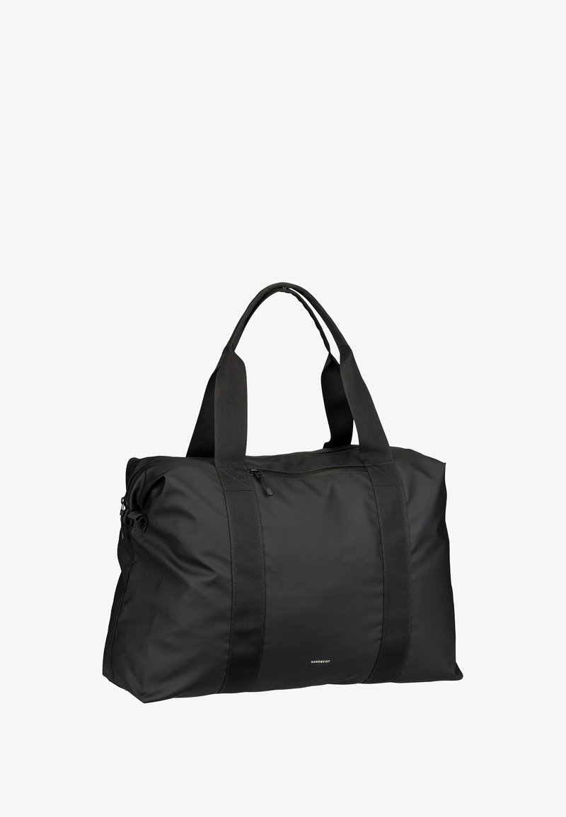 Sac polochon noir en nylon durable avec deux poignées solides et une fermeture éclair sur le dessus. Présente une texture lisse et un marquage minimaliste.