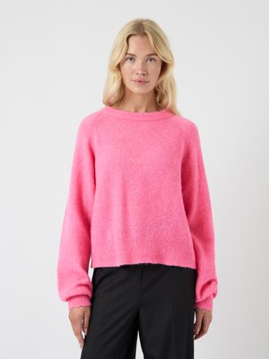 Felle roze trui gemaakt van zacht, pluizig materiaal. Hij heeft een ronde halslijn, lange mouwen en een iets verkorte zoom.