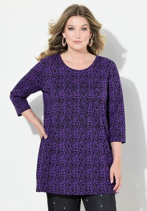 Lilla tunika med sort leopardprint, rund halsudskæring og trekvartærmer. Blød tekstur med synlige lommer foran.