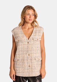 Beige Tweed-Weste mit V-Ausschnitt, kurzen Ärmeln und zwei Vorderaschen. Aus strukturiertem Stoff mit mehrfarbigen Fäden und goldenen Knöpfen.