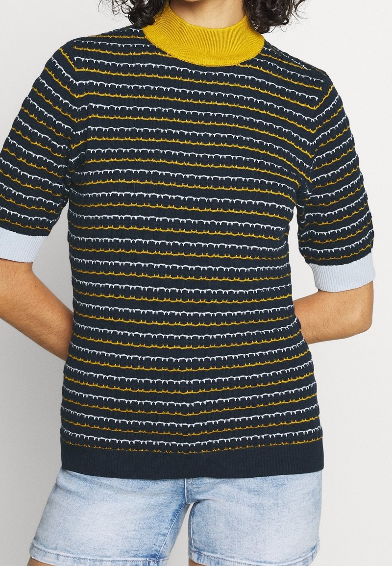 Stickad kortärmad topp med marinblå, gul och vit randning, med en gul hälsguide och ljusblå detaljer på ärmarna.