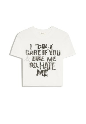 Biały krótki t-shirt z czarnym postarzałym napisem "I don't care if you like me or hate me" i małą grafiką gwiazdy.