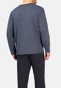 Marineblaues Langarmhemd mit dünnen weißen Streifen, runder Ausschnitt und aus weichem Stoff, kombiniert mit dunklen Hosen. Schlichtes und lässiges Design.