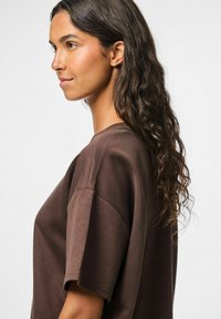 T-shirt oversize marrone in morbido tessuto, con collo a giro e maniche corte, dalla silhouette rilassata e con cuciture minime.