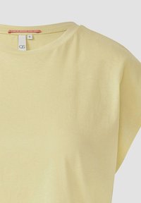 Lichtgele t-shirt met korte mouwen en ronde hals, gemaakt van zachte katoenstof. Inclusief een label met de tekst "FUN IS WHERE YOU ARE".