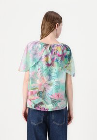 Transparante blouse in pastelkleuren met bloemmotieven, een ronde halslijn en een knoopsluiting aan de achterkant. Vloeiende, lichte stof.