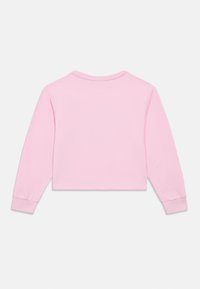 Μπλούζα cropped με μακριά μανίκια σε ανοιχτό ροζ βαμβάκι, με στρογγυλεμένο λαιμόκομμα και εφαρμοστά μανικετόκουμπα. Λείο ύφασμα, μινιμαλιστικός σχεδιασμός.