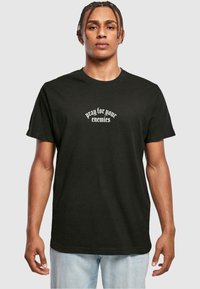 Black cotton t-shirt featuring the text "pray for your enemies" in white. Classic fit with short sleeves and a round neckline.