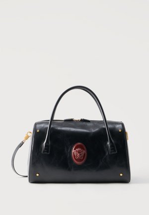 Black leather handbag with two handles, gold hardware, and a central red oval emblem featuring a Medusa head design.