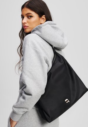 Black nylon tote bag with a sleek design, featuring a smooth texture, zip closure, and a small branded accent on the side.