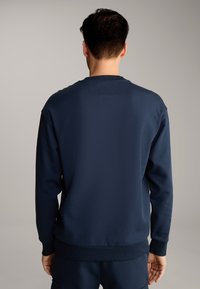 Felpa blu navy con scollo a giro, polsini e orlo a costine. Realizzata in tessuto morbido con una texture liscia, adatta per un abbigliamento casual.