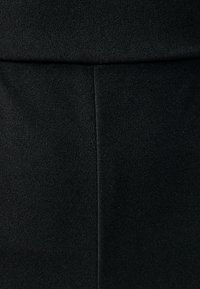 Sort stof med en glat tekstur, der har en central søm der løber lodret, hvilket skaber et strømlinet udseende.