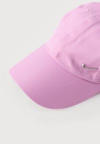 Ανοιχτό μωβ καπέλο μπέιζμπολ με καμπύλη γείσο και μικρό μεταλλικό λογότυπο Nike Swoosh στο μπροστινό δεξί μέρος, σε λευκό φόντο.