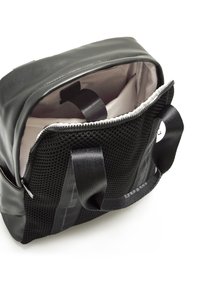 Bolsa negra con una textura suave, laterales de malla y una apertura con cremallera. El interior cuenta con un tejido claro y asas dobles para llevar.