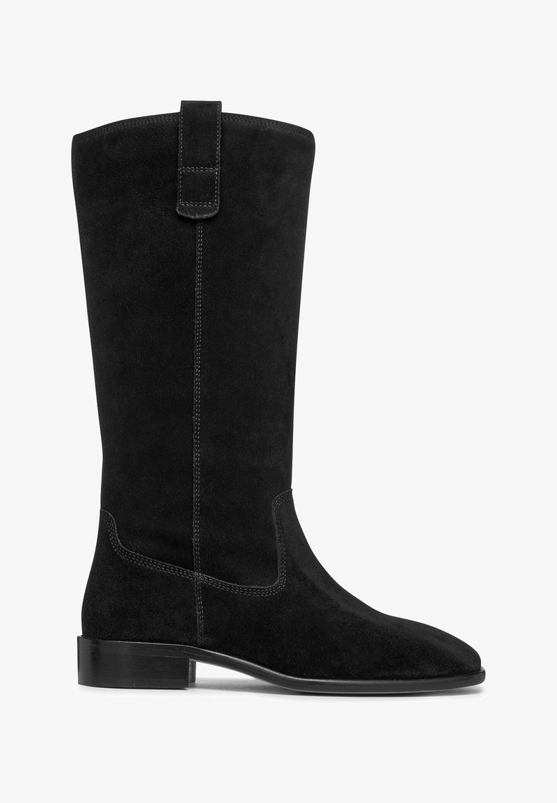 Bota de ante negra hasta la rodilla con una textura suave, puntera afilada y tacón bajo apilado. Presenta costuras en contraste y una lengüeta en la parte superior.