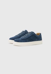 Tamno plave suede tenisice s bijelim gumenim đonom, s okruglim vezicama i elegantnim, minimalističkim dizajnom.