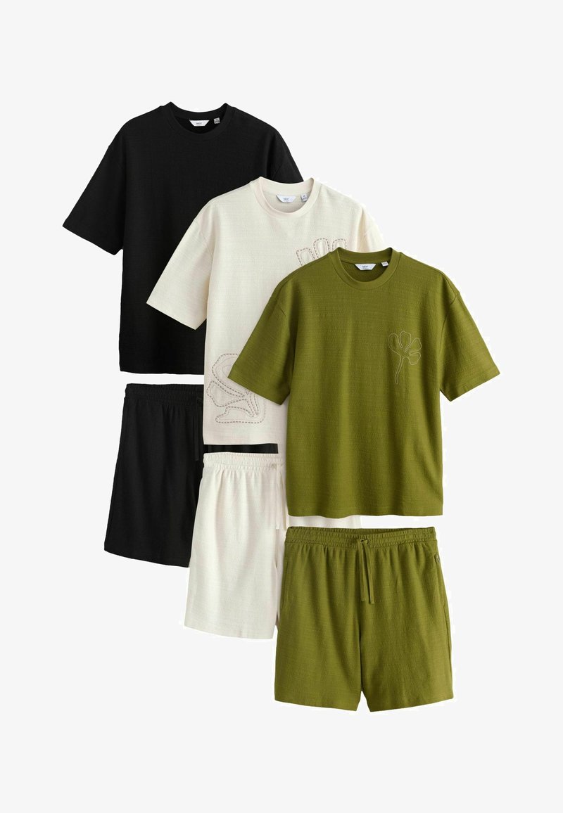 Trois ensembles de chemises à manches courtes et shorts en noir, blanc et vert olive, avec une broderie discrète de feuilles sur les chemises blanches et olive.